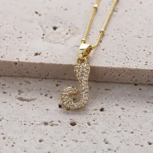 Gros plan détaillé d'un collier chaîne en cuivre doré avec pendentif lettre J en zircon.