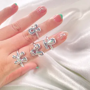 Primo piano dettagliato di anelli con lettere lisce e spesse al dito, gioiello argento trendy.
