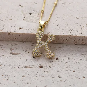 Gros plan détail d'un collier pendentif lettre K en cuivre plaqué or micro-serti de zircon.