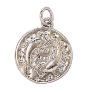 Close-up detail of vintage round Pisces zodiac pendant, silver tone metal craft accessory.