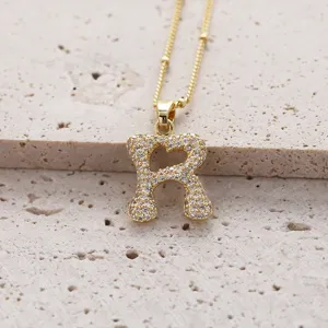 Gros plan détaillé d'un magnifique collier pendentif lettre R en zircone pavé or.