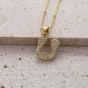 Gros plan détail du pendentif lettre en zircon micro-pavé scintillant sur surface texturée.