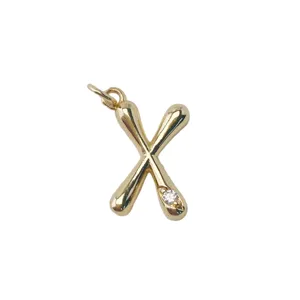 Detail shot of a elegant gold plated letter X pendant accessory with sparkling gemstone detail.
