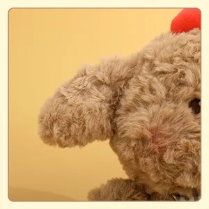 Nahaufnahme des braunen Plueschwelpen, weiches flauschiges Fell und kariertes Halsband Design.
