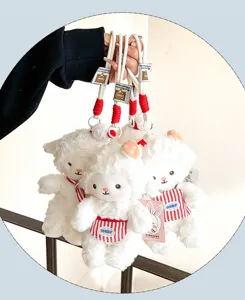 Cute white lamb plush toy keychain featuring a red striped apron, soft and fluffy bag charm.