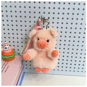 Primo piano del portachiavi maialino in peluche rosa appeso al pannello forato, ciondolo borsa.