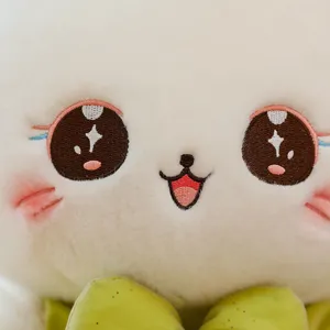 Cute white cat plush toy close-up face with detailed embroidered big eyes and green bow.