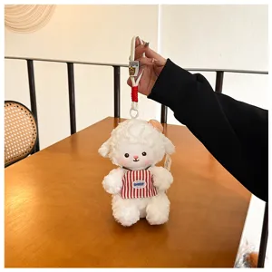 Detailed close-up of a cute plush lamb keychain pendant with red striped apron and lanyard.