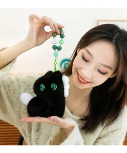 Close-up detail view of the cute plush pendant with green eyes and beaded strap in use.