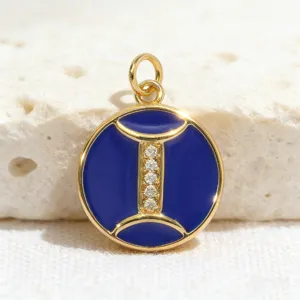Close-up detail of gold-plated round zodiac pendant with blue enamel and sparkling zirconia.