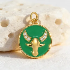 Detailed close-up of a gold-plated green enamel Taurus zodiac charm with sparkling zircons.