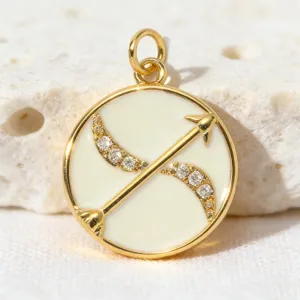 Detail view of gold plated round zodiac arrow pendant with white enamel and sparkling zircon stones.