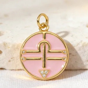 Detail shot of the round pink enamel zodiac pendant featuring sparkling cubic zirconia in gold-plated copper.