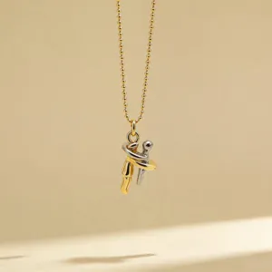 Detail shot of a minimalist two-tone hugging figures pendant necklace with delicate beaded chain.