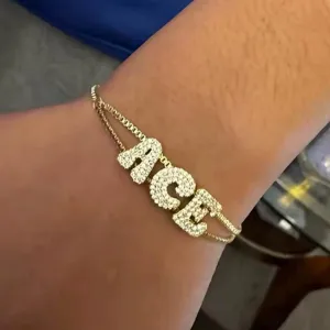 Detail shot of the custom letter charm bracelet featuring sparkling cubic zirconia stones on gold.