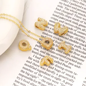 Nahaufnahme von glitzernden Strass-Buchstabenanhängern und filigraner goldener Halskette Detail
