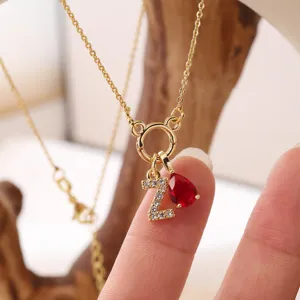 Dettaglio di collana con lettera Z placcata oro, preziosa pietra di nascita e goccia rossa.