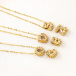 Nahaufnahme glänzender Pave-Buchstaben-Anhänger Halsketten in edler Gold-Optik.