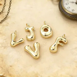 Primer plano detallado de dijes de letras doradas brillantes, perfectos para accesorios de joyería.
