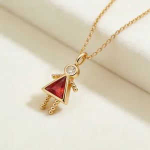 Detalle de collar con colgante de niña de oro con cuerpo de piedra roja y cabeza brillante.