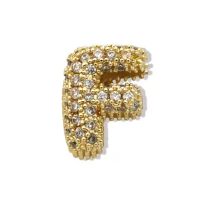 Nahaufnahme eines goldenen Buchstaben-F-Anhängers, funkelnd besetzt mit feinen Zirkoniasteinen.