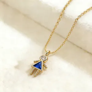 Primer plano detallado de un delicado collar con dije de niña chapado en oro brillante.