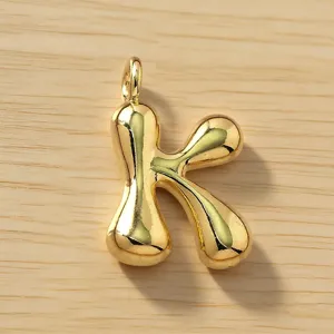 Colgante de letra K abombada dorada en detalle, elegante abalorio metálico inicial.