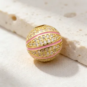 Détail en gros plan d'une perle pendentif basket en plaqué or avec zirconiums et émail rose.