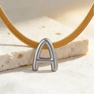 Nahaufnahme Detail des silbernen Buchstaben A Anhängers an Goldkette, edles Schmuckstück.