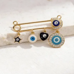 Close-up detail view of trendy gold evil eye safety pin brooch with sparkling charms.