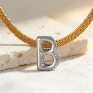 Nahaufnahme Detail einer minimalistischen Silber Buchstabe B Anhänger Kette in Gold und Silber.