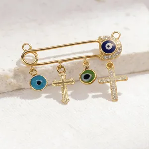 Gold evil eye safety pin pendant cross charm stylish jewelry accessory fashion piece.
