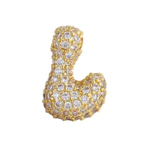 Dettaglio in primo piano di un ciondolo a lettera dorato con pavé di zirconi luminosi.