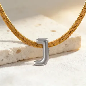 Nahaufnahme des eleganten silbernen Buchstaben J Anhängers mit goldener Schlangenkette.