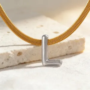 Nahaufnahme der goldenen Fischgrätkette mit einem eleganten silbernen Buchstaben L Anhänger.