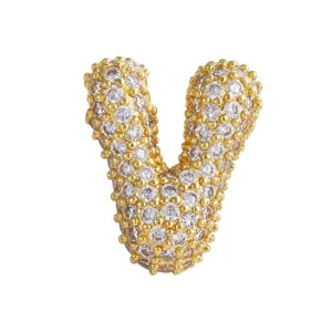 Dettaglio ciondolo lettera V in zircone dorato, accessorio collana hip-hop scintillante.