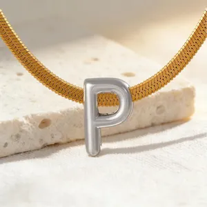 Detailansicht einer goldenen Schlangenkette mit silbernem Buchstaben P Anhänger auf Stein.