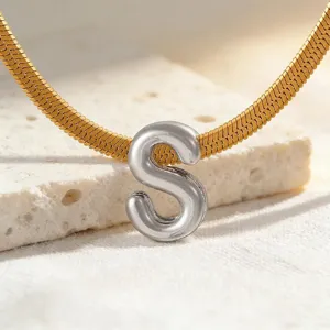 Detailaufnahme einer goldenen Schlangenkette mit silbernem Buchstaben S Anhänger, Schmuck.
