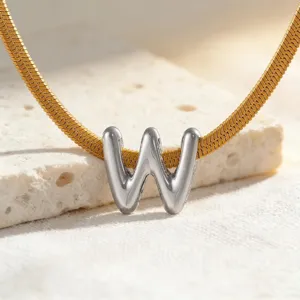 Nahaufnahme einer goldenen Schlangenkette mit silbernem W Buchstaben Anhänger für Damen.