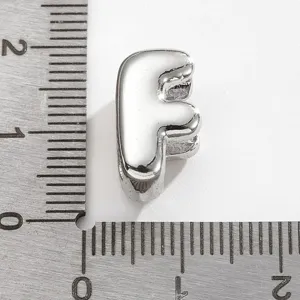 Gros plan détaillé du pendentif en métal argenté lettre F accessoire pour la bijouterie.