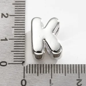 Gros plan du pendentif lettre K en métal avec une règle pour indiquer la taille précise.