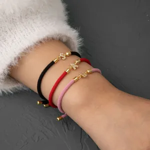 Gros plan de bracelets en cordon tressé réglable avec des charms lettres en zircone scintillante.