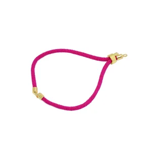 Primo piano del dettaglio del bracciale intrecciato in nylon rosa con cursore metallico dorato.