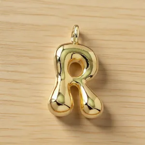Detalle de primer plano de un bonito colgante de letra R dorada abultada para joyería.