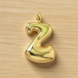 Detalle de colgante burbuja letra número abultado dorado, brillante joya de metal.