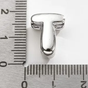 Gros plan sur la perle pendentif lettre T en métal argenté avec échelle de mesure.