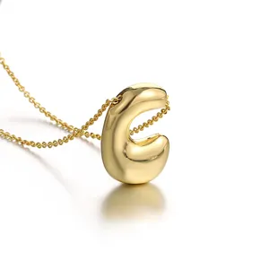 Gold plated puffy letter C pendant necklace close up, delicate chain jewelry detail.