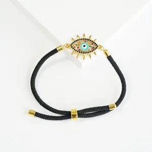 Bracciale regolabile in corda nera intrecciata con ciondolo a forma di malocchio dorato e cristalli.