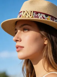 Women's straw sun hat with stylish ribbon and metal letter decoration for summer outdoor wear.