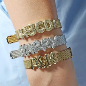 Dettaglio di bracciali con cinturino a maglia e lettere in zirconi micro-incastonati.